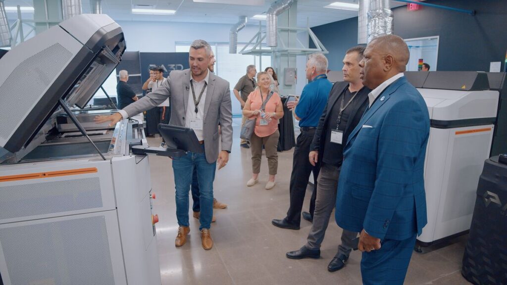 A3D Manufacturing employee showing 3D printer to professionals